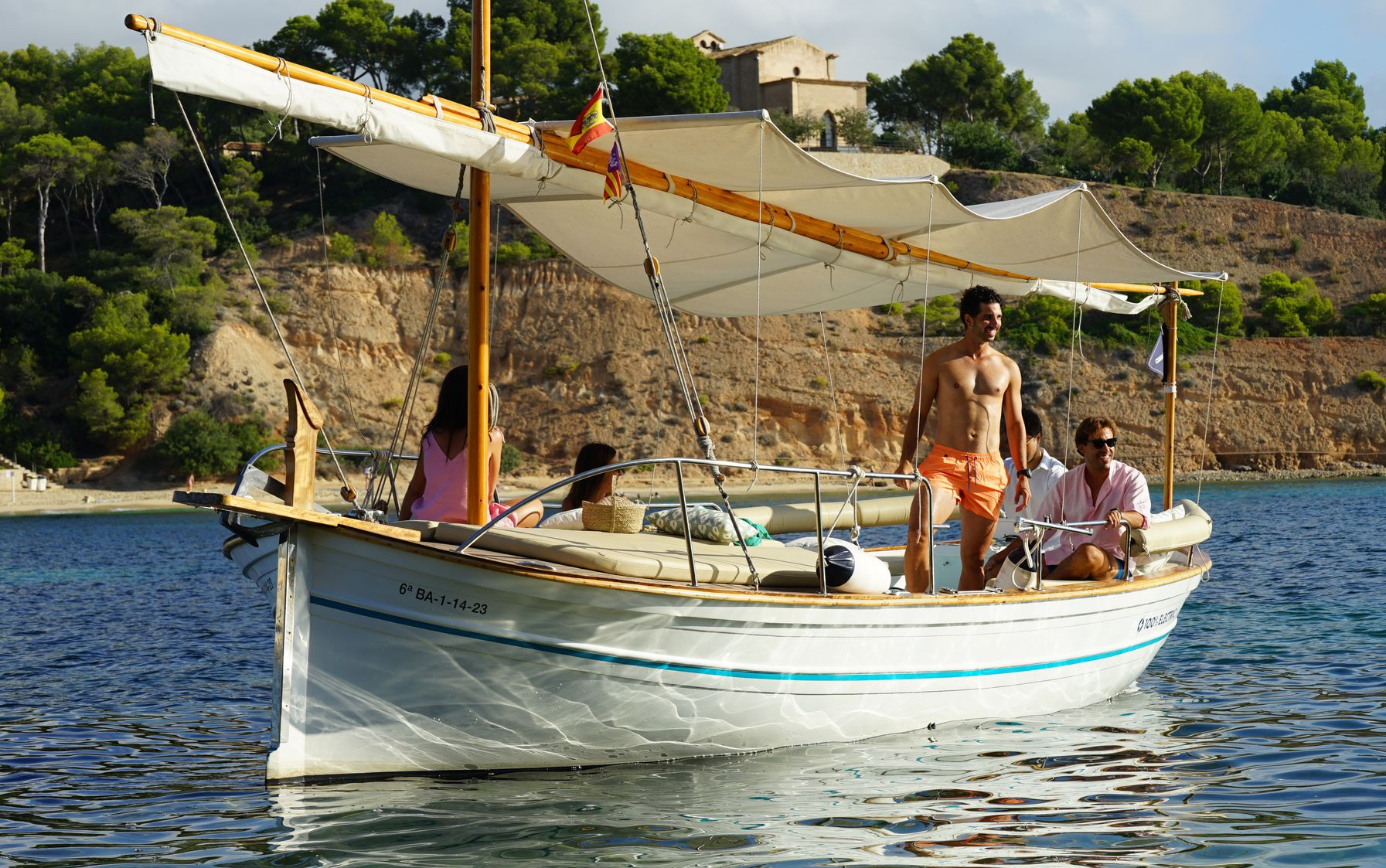 Pareja disfrutando de comida y bebida en un romántico paseo en llaut por el mar de Mallorca, ideal para alquiler de llaut