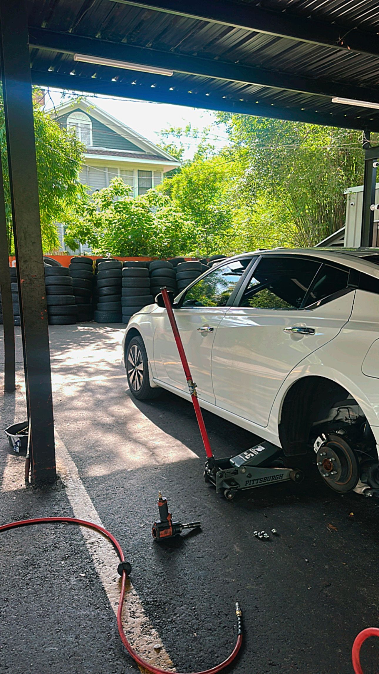 Red classic car lifted on a garage hoist with a vehicle frame below in a workshop. | Eagle Tires