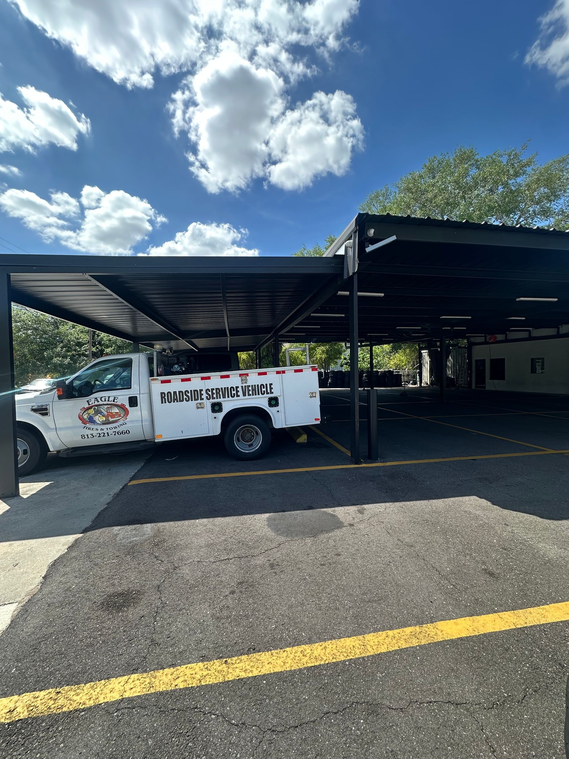 Mechanic changing a tire on a black car under an Eagle Tires service canopy | Eagle Tires