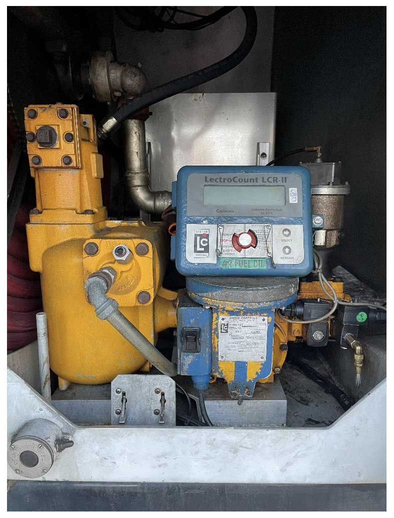 A yellow industrial fluid meter and pump unit with a blue electronic display housed within a metal cabinet.