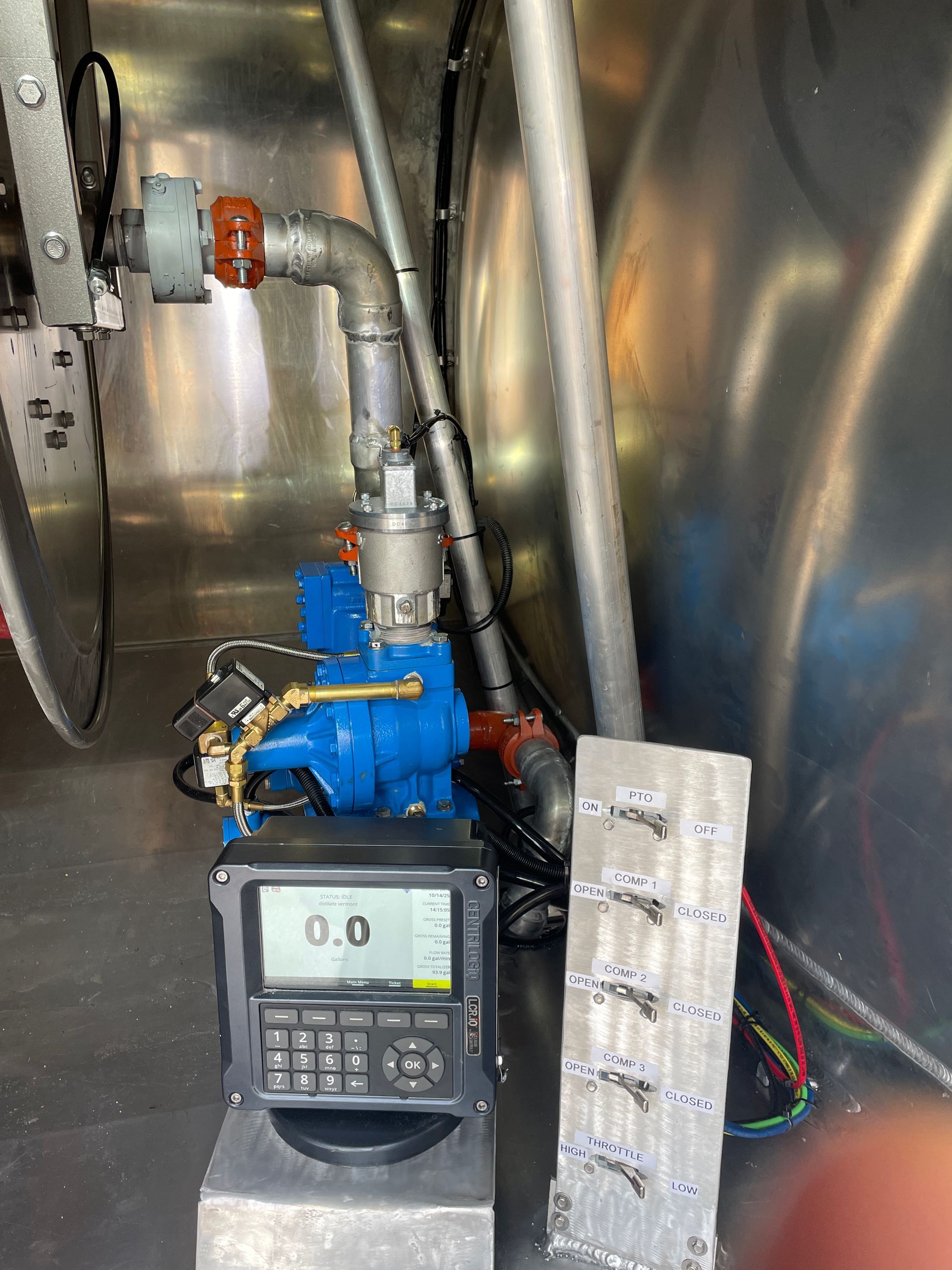 A blue pump and a digital meter displaying 0.0, positioned next to a vertical panel of manual switches inside a metal unit.