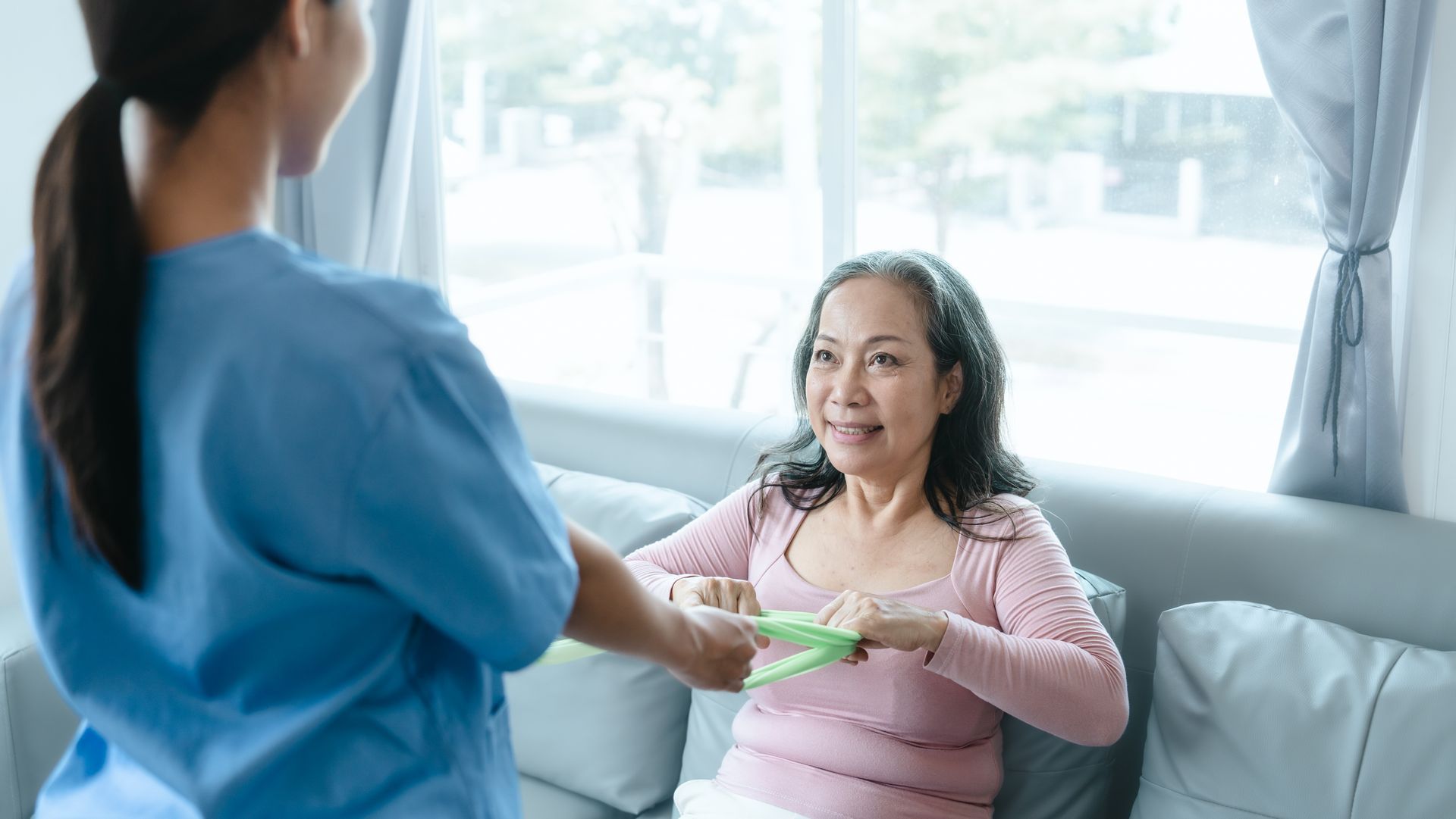 A nurse is talking to an elderly woman sitting on a couch.