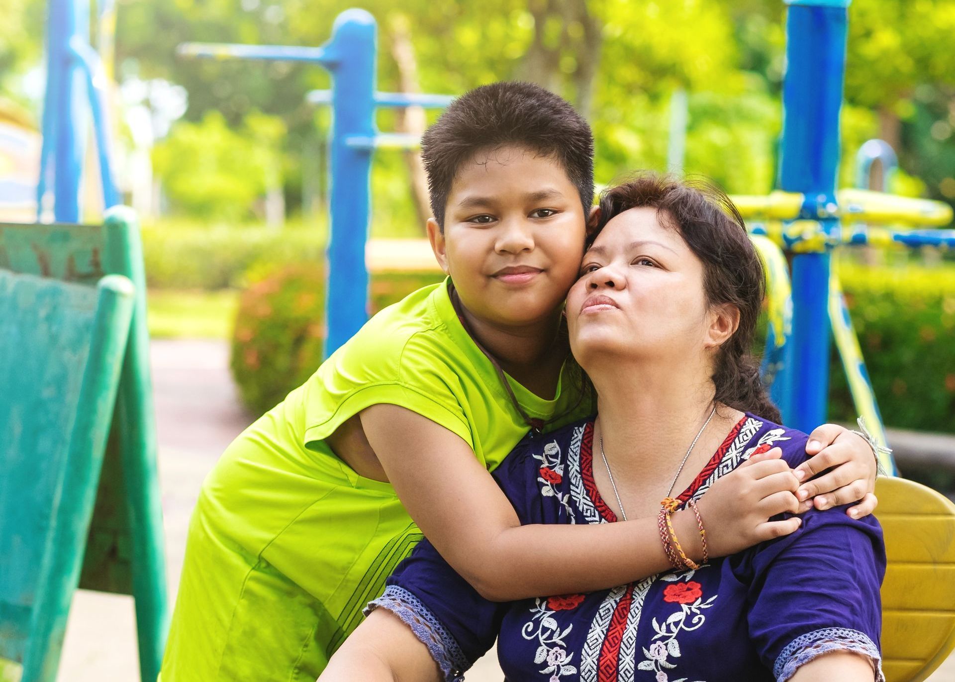 A boy is hugging a woman in a park.