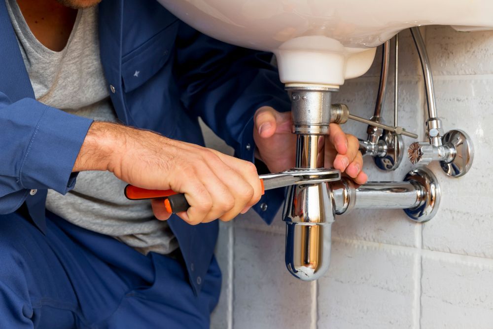 Plumber Tightening a Bathroom Sink Drain Pipe — One Flush Plumbing Service In Ormeau, QLD