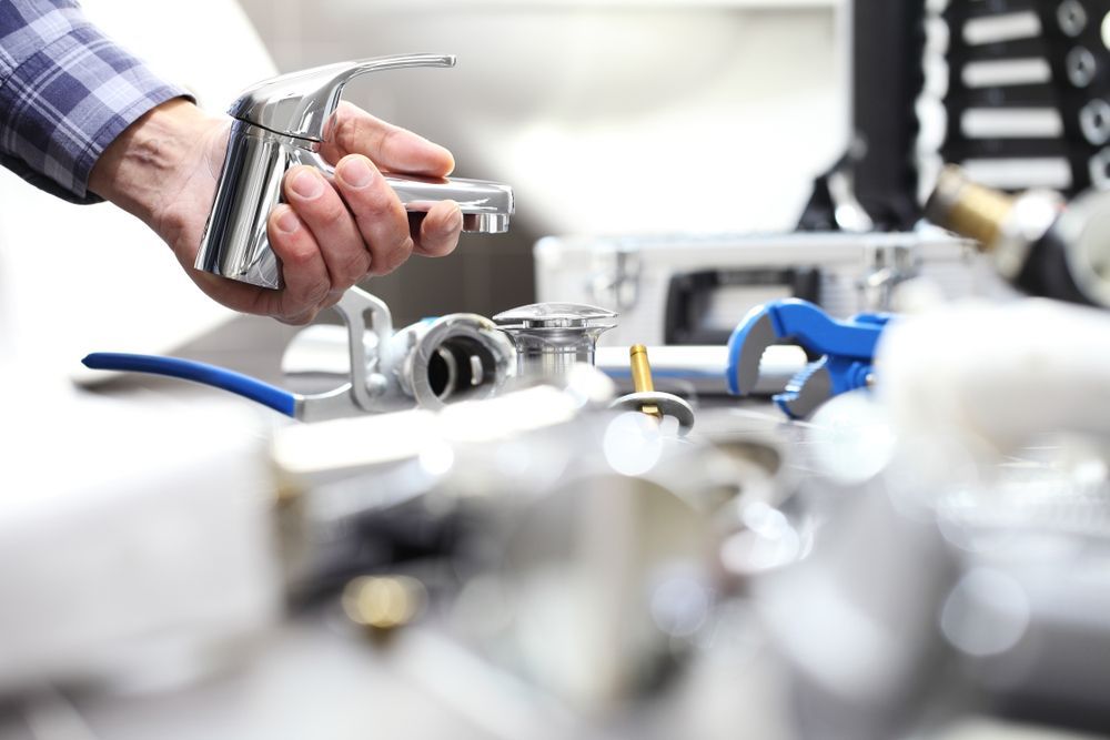 Hand Holding a Spray Nozzle Over a Sink — One Flush Plumbing Service In Helensvale, QLD