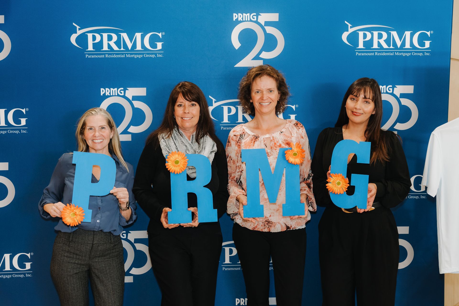 Four PRMG team members holding letters spelling PRMG at the company's 25th anniversary celebration