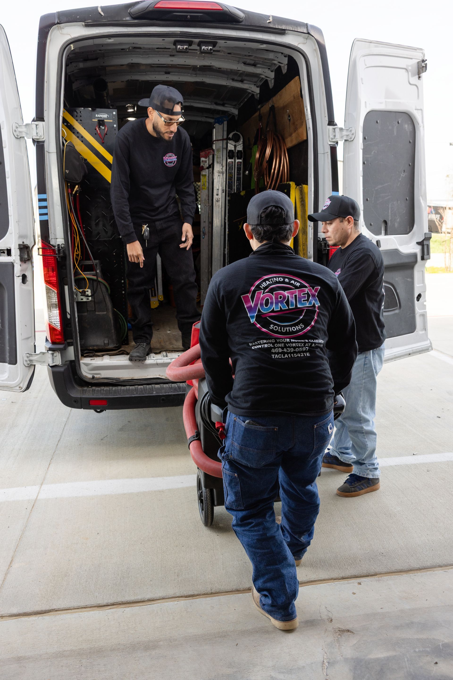 Man in attic inspecting insulation. Pink insulation covers the floor, ductwork visible.