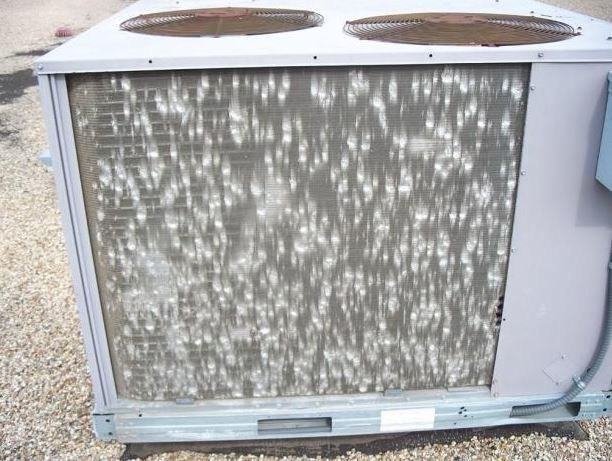 Outdoor HVAC condenser unit with two top fans and a dirty front grille