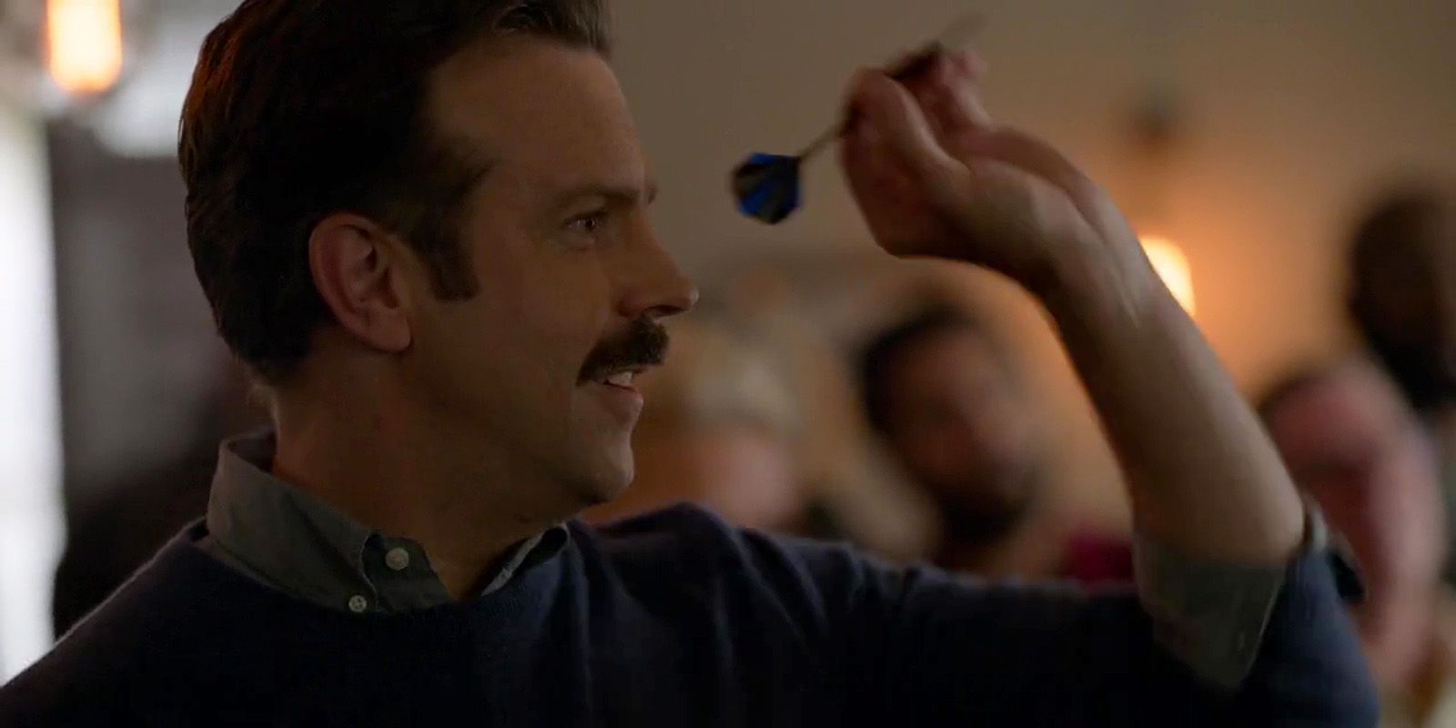 A man with a mustache is throwing a dart in the air.