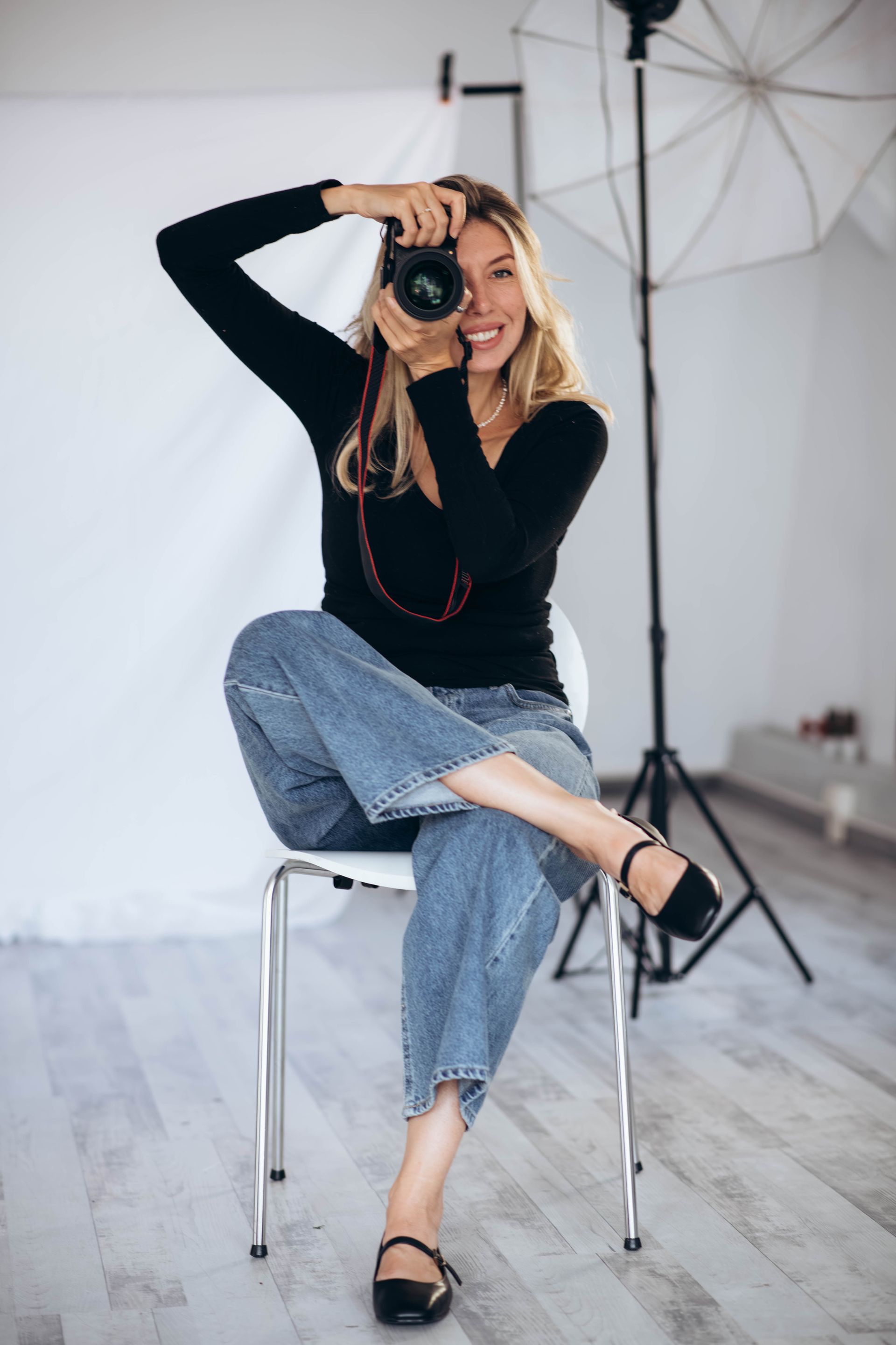 A woman is sitting on a chair taking a picture with a camera.