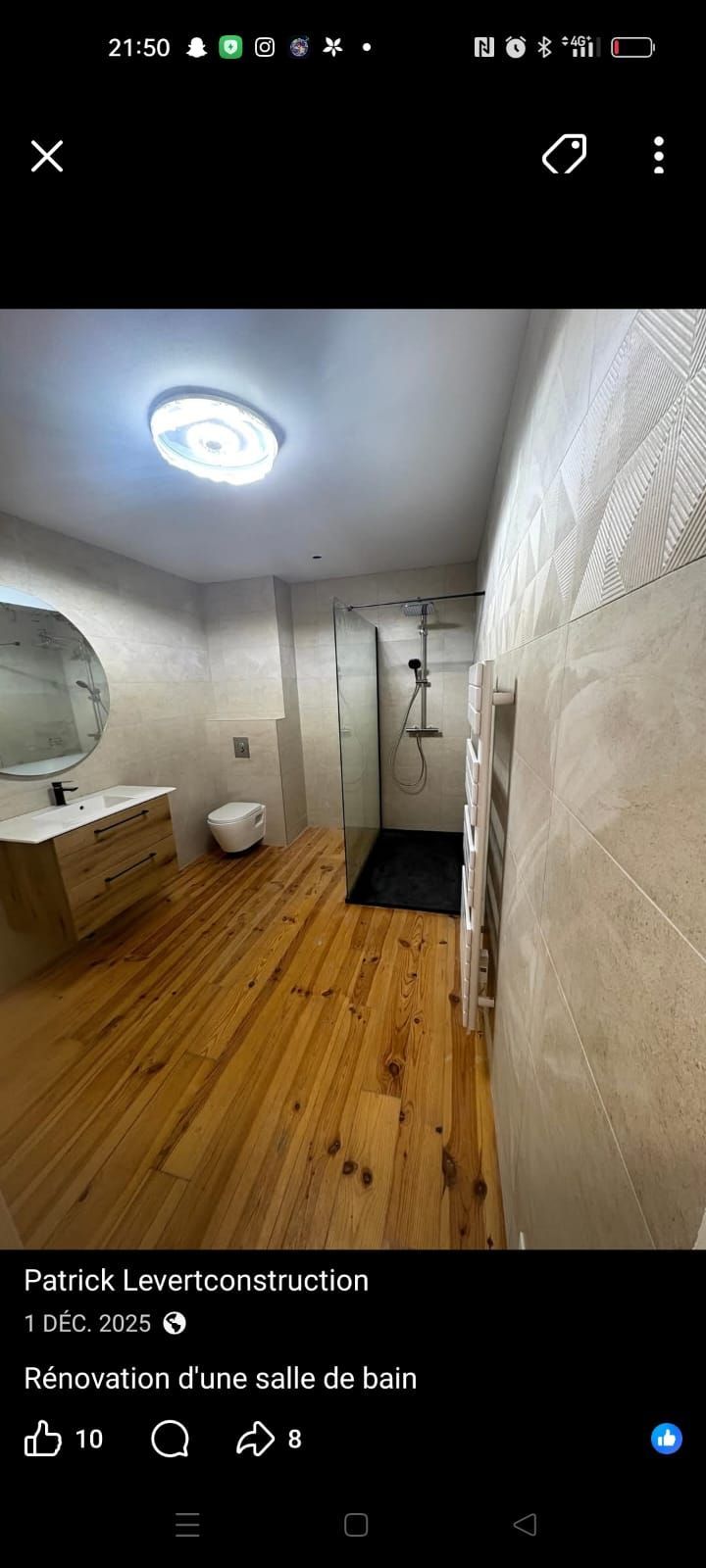 Salle de bains moderne avec parquet, cabine de douche blanche, toilettes et lavabo sous un éclairage lumineux au plafond.