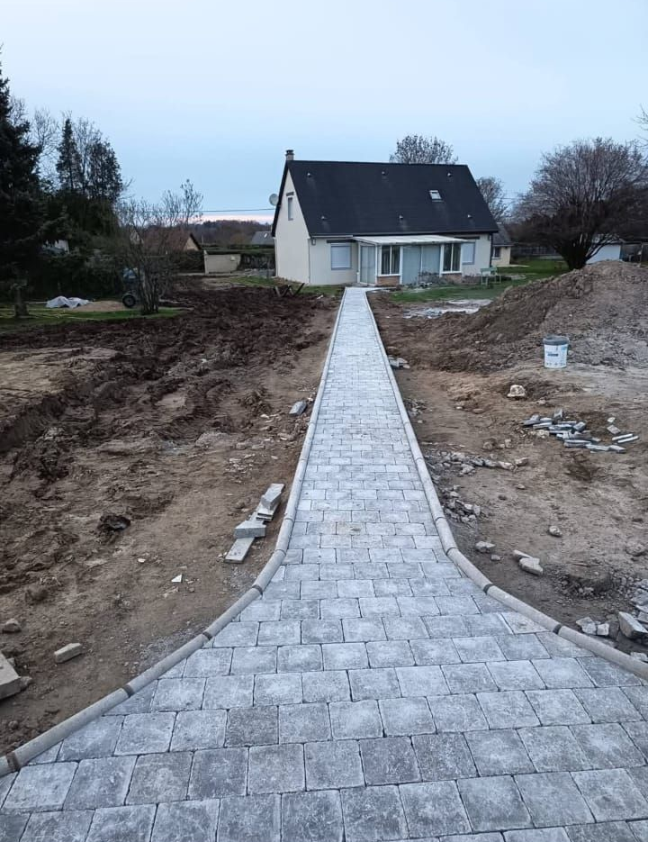 Chemin de pierres en construction menant à une maison blanche dans une cour de campagne