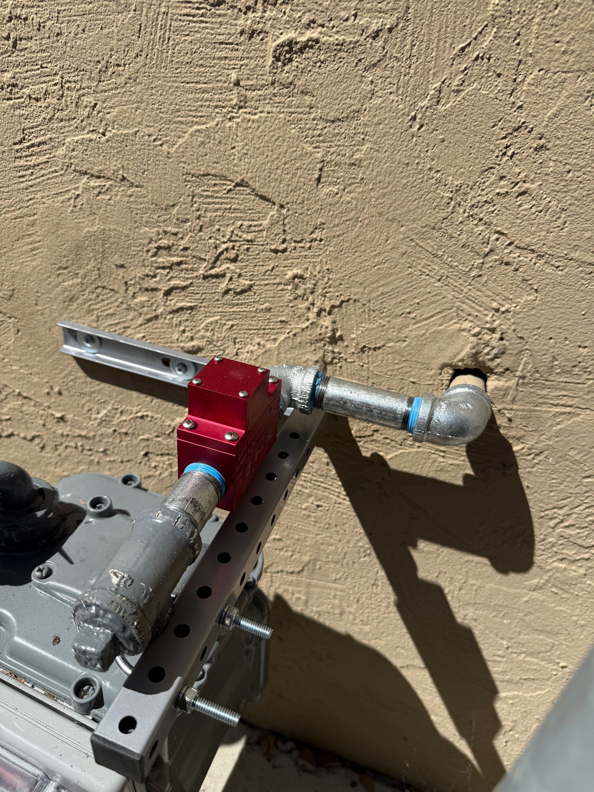 Plumber adjusting a valve on copper pipes with a pressure gauge, holding a wrench.