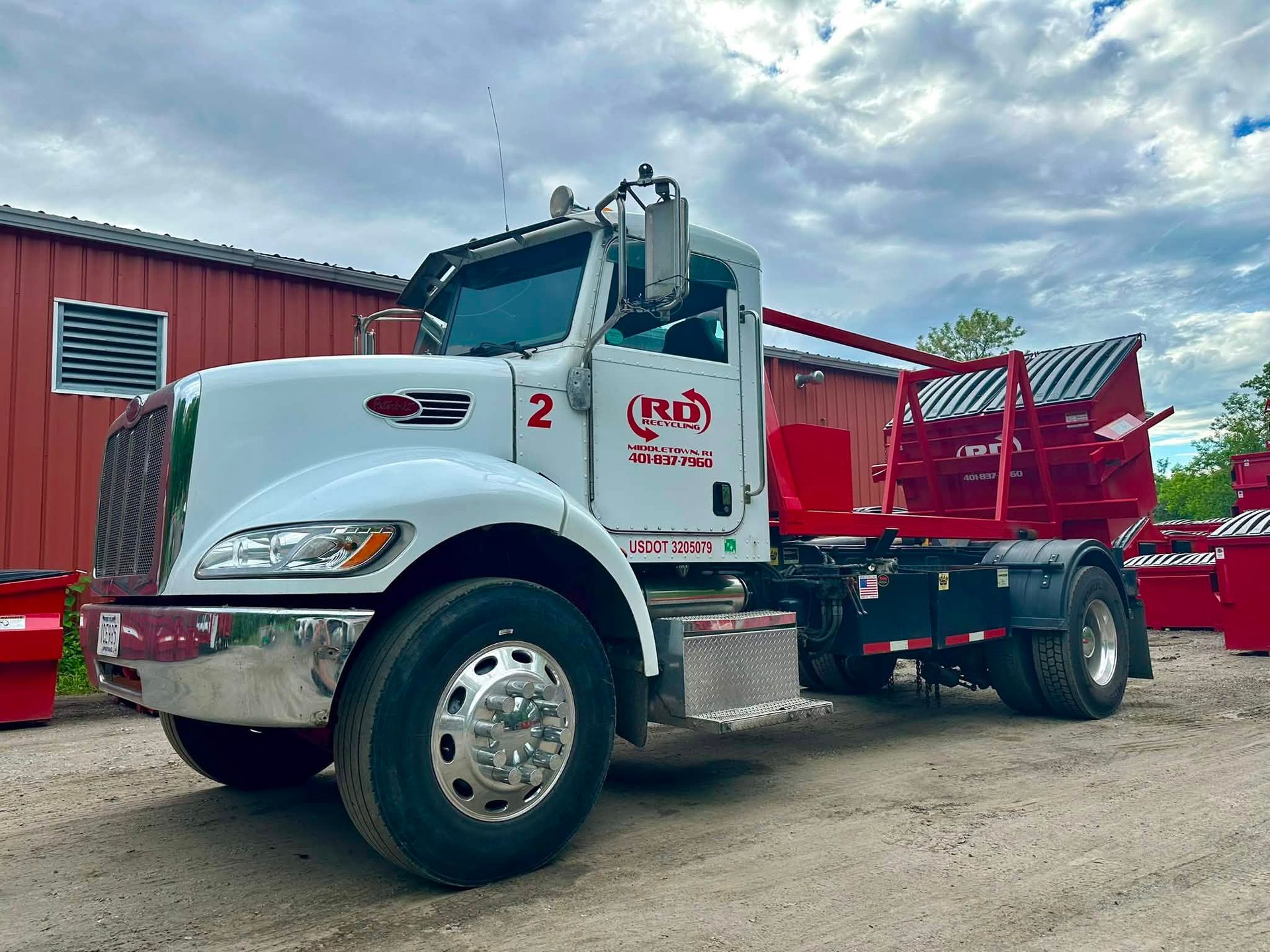 White and red dump truck parked outdoors beside a red building