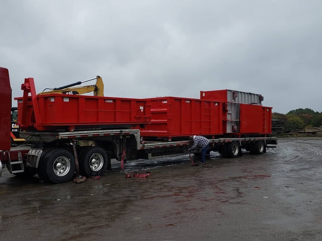 Red flatbed truck trailer parked on a wet lot under a cloudy sky
