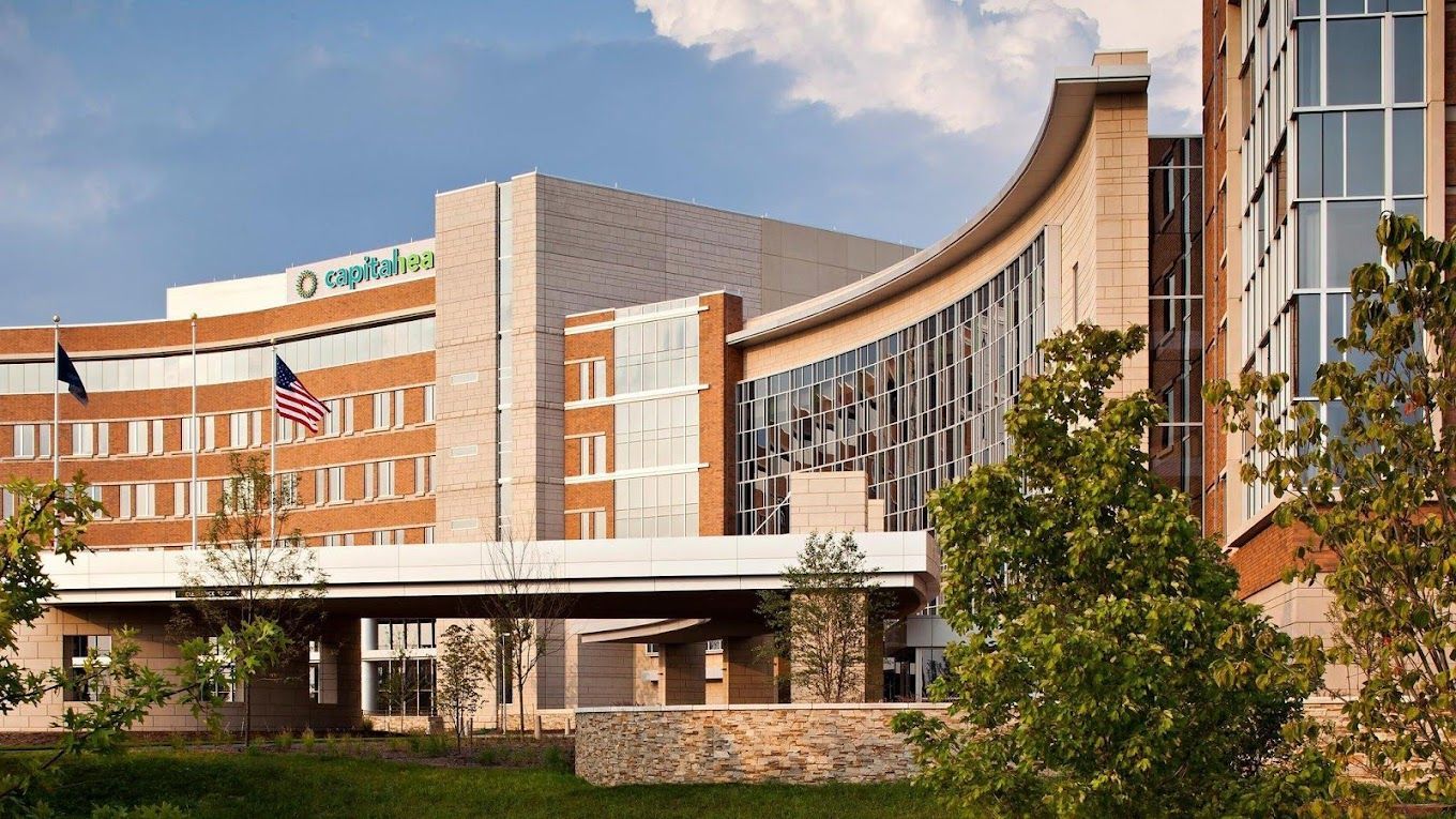 A large building with a lot of windows is surrounded by trees and grass.
