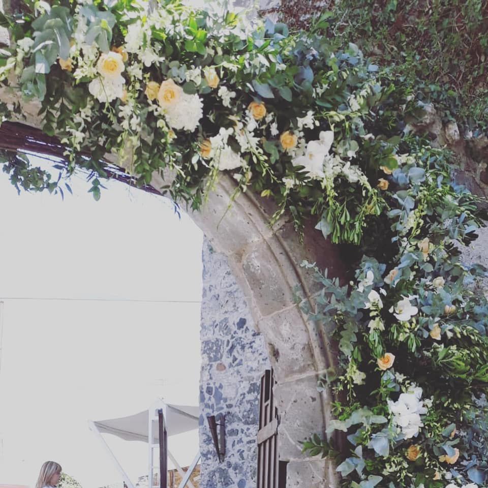 Un arco in pietra è decorato con fiori e verde