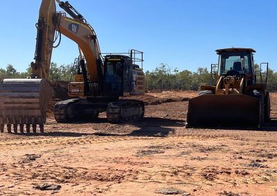 Excavator and loader on construction site, sunny day.