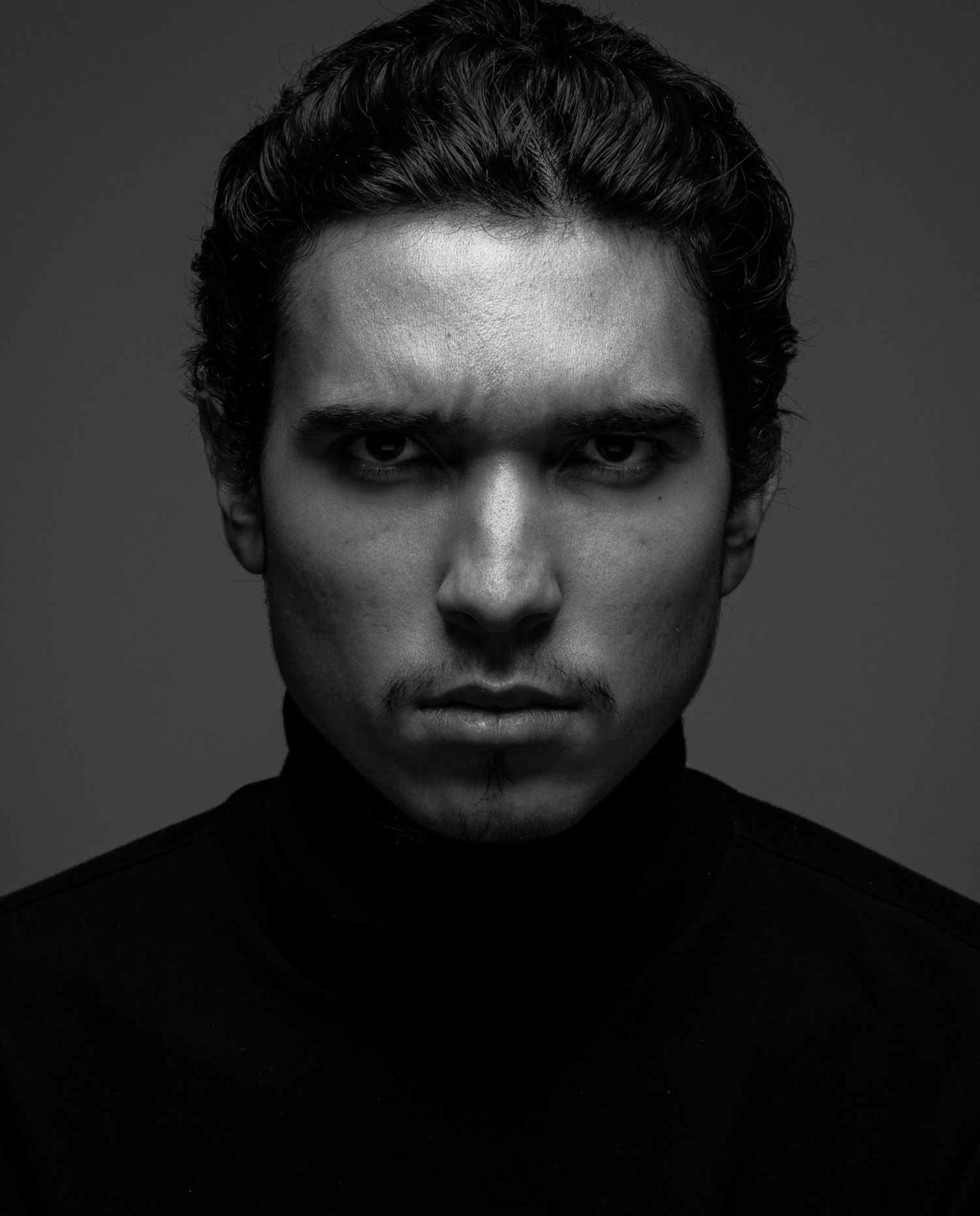A black and white photo of a man wearing a black turtleneck.