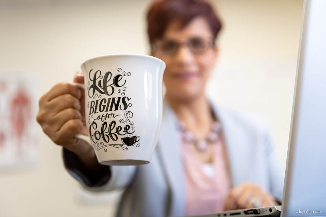A woman is holding a coffee mug that says life begins after coffee