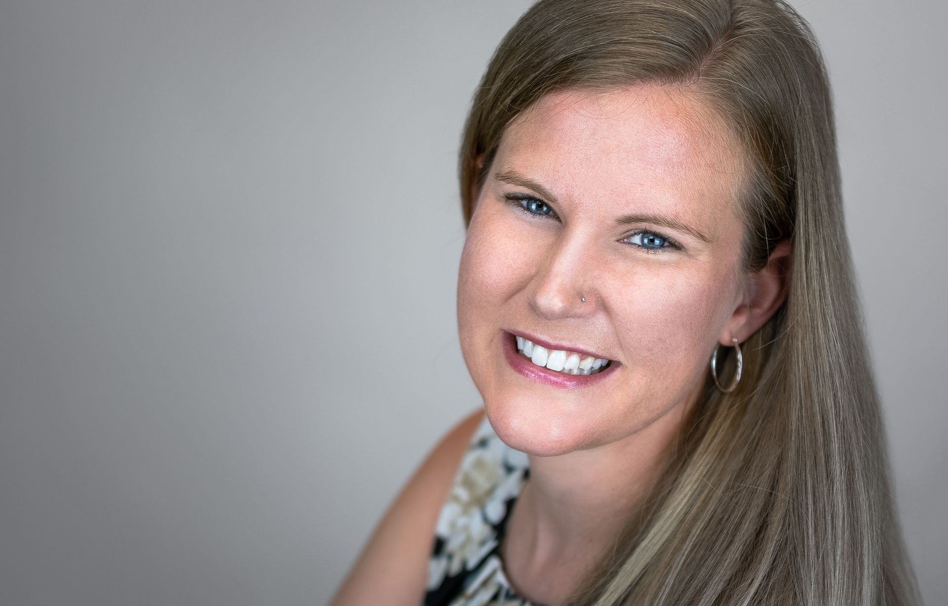 A woman with long hair and freckles is smiling for the camera.
