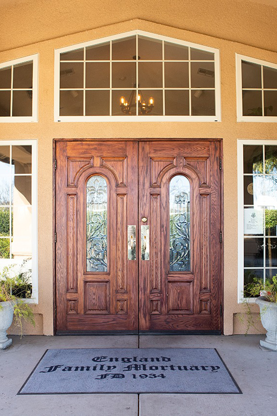 Wooden double doors with glass panes, above a gray mat reading
