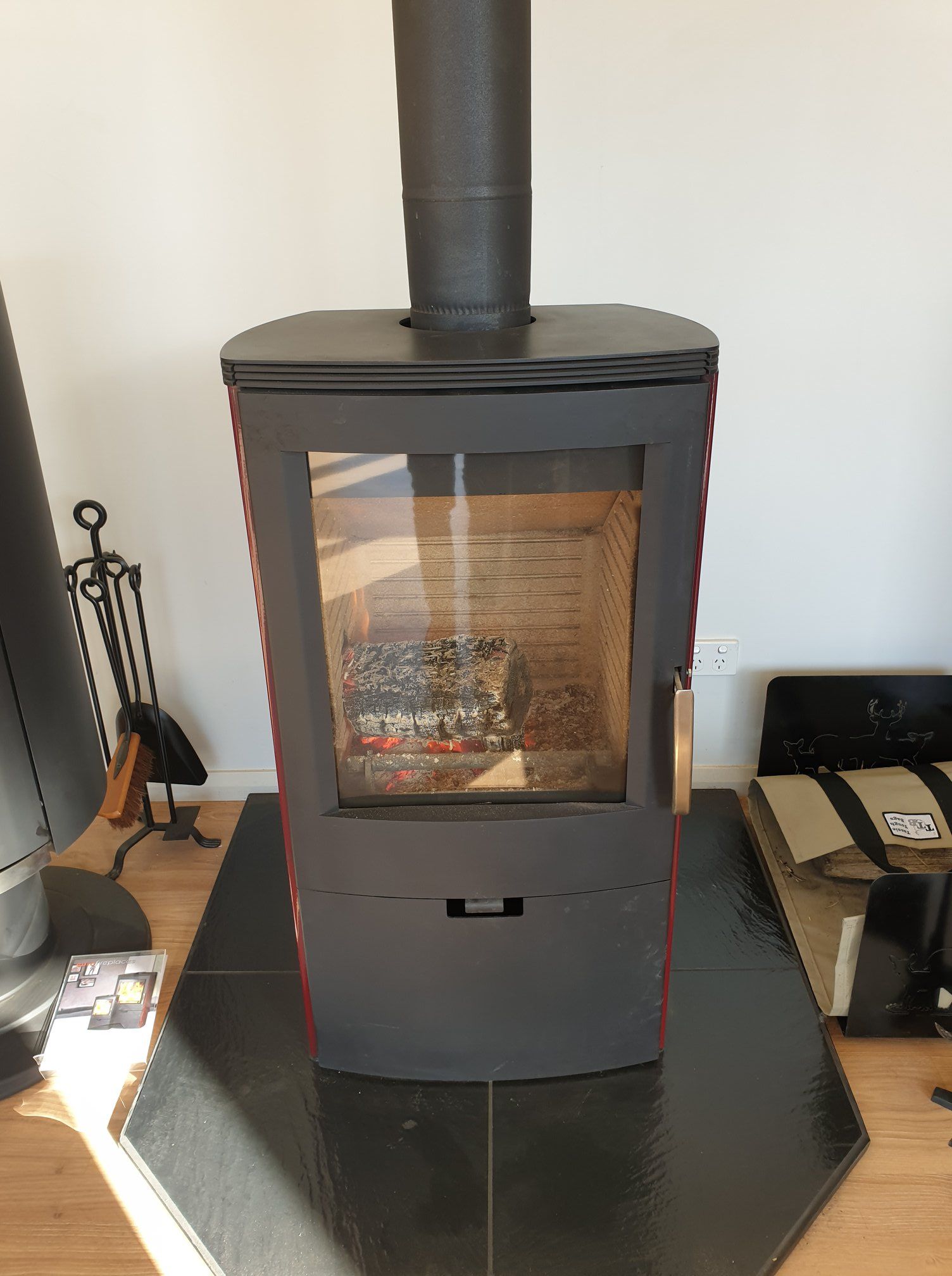 A Black, Modern Wood-burning Stove Sits on a Dark, Tiled Hearth — Complete Heating In Huntingfield, TAS