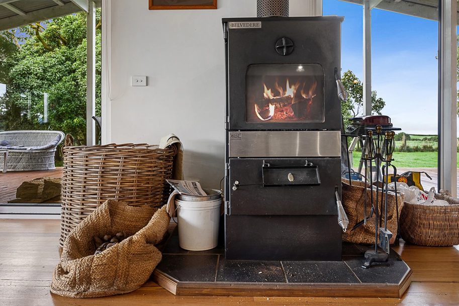 Wood-burning Stove on a Wooden Floor With Baskets and Firewood — Complete Heating In Huntingfield, TAS