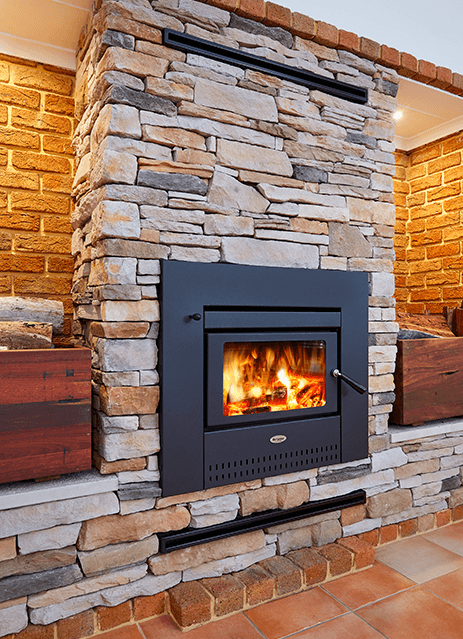 Stone Fireplace With a Lit Black Wood Stove and Terracotta Tile Hearth — Complete Heating In Huntingfield, TAS