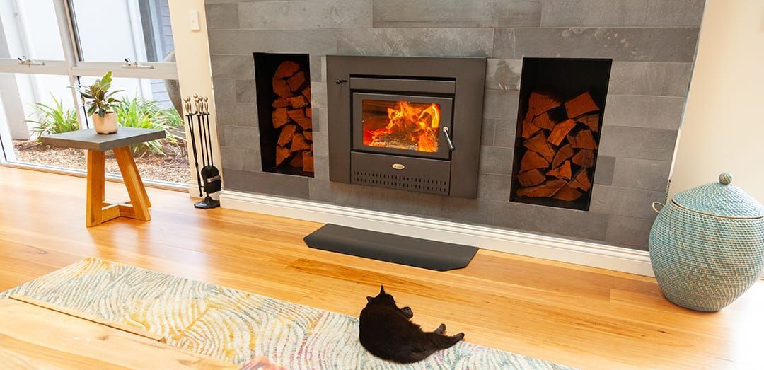 Living Room With a Lit Fireplace, Cat on a Yellow Rug, and Decorative Vases — Complete Heating In Huntingfield, TAS