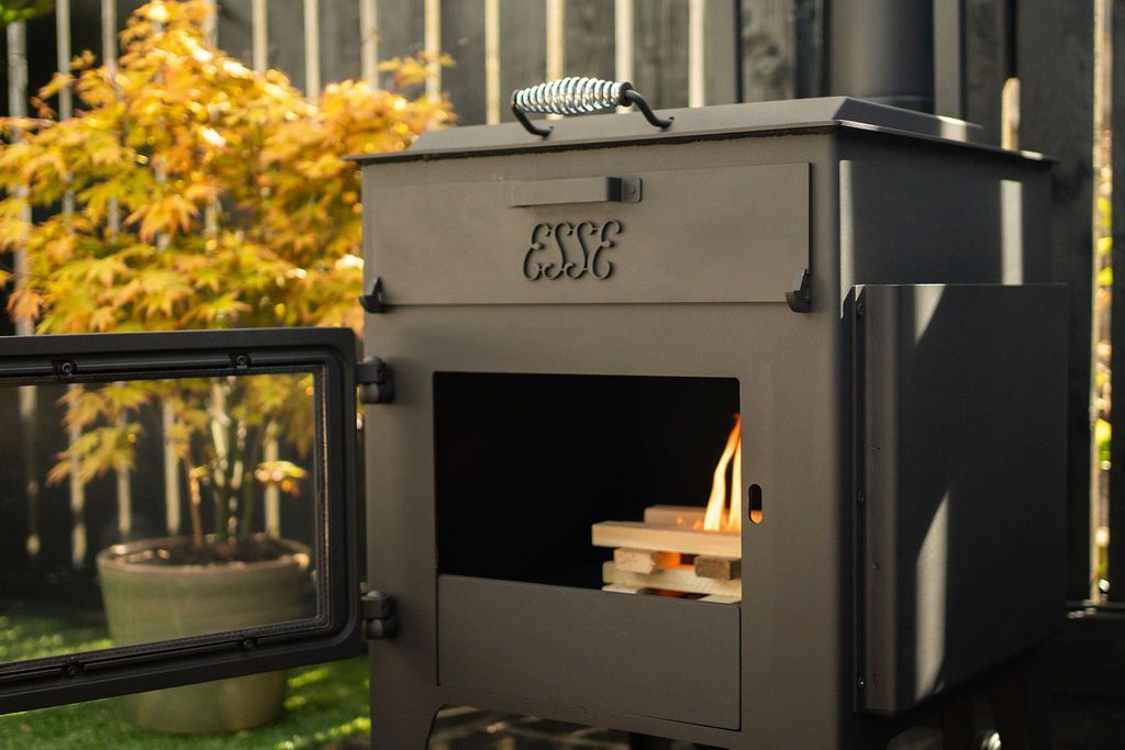 Black Outdoor Smoker Grill With Fire Glowing Inside on a Patio — Complete Heating In Huntingfield, TAS