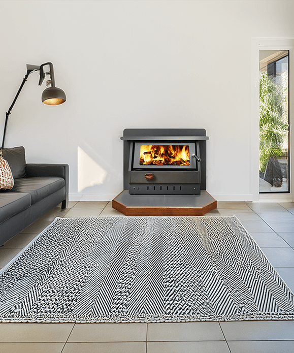 Modern Living Room With a Lit Fireplace, Grey Sofa, Floor Lamp, and Patterned Rug — Complete Heating In Huntingfield, TAS