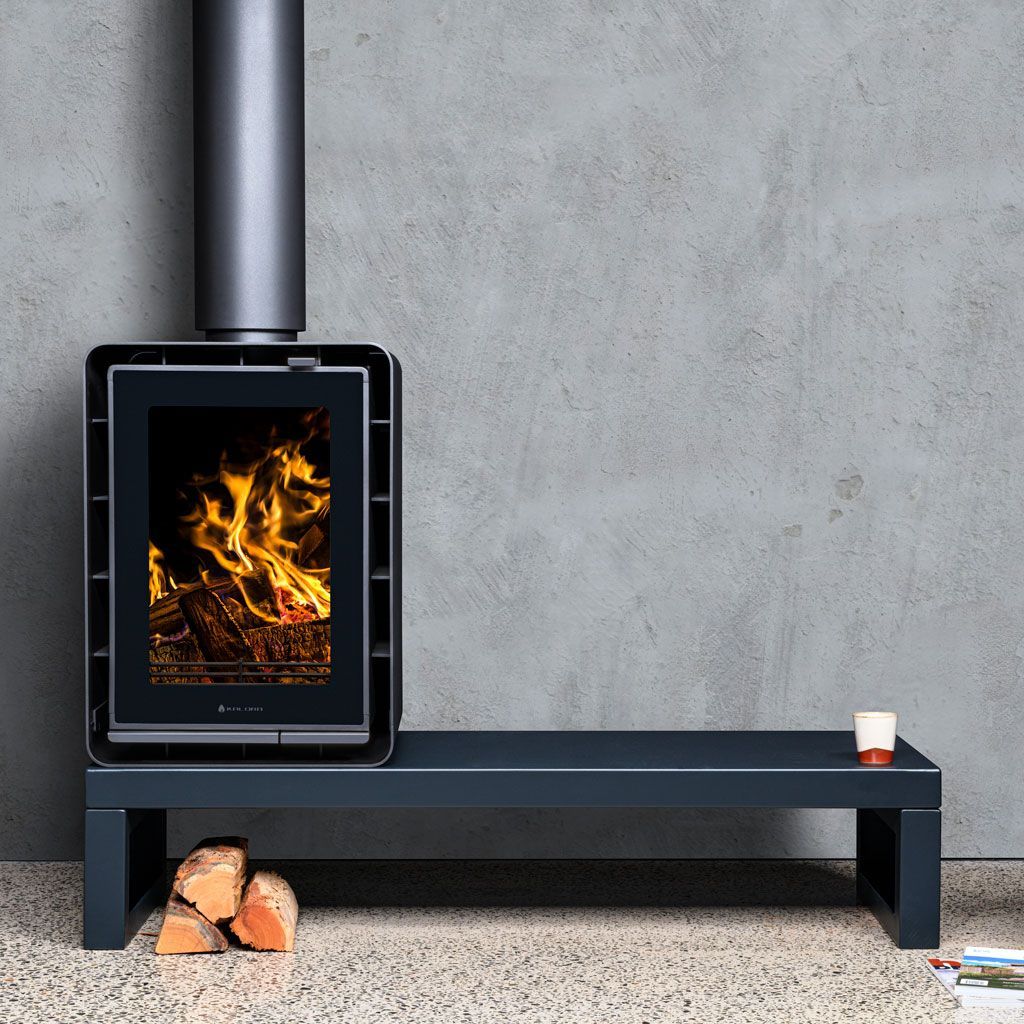 Black Wood-burning Stove With a Fire, on a Bench Against a Grey Wall — Complete Heating In Huntingfield, TAS