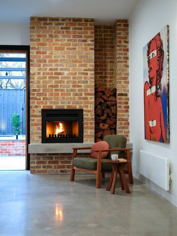 Living Room With Brick Fireplace, Two Chairs, and Wall Art — Complete Heating In Huntingfield, TAS
