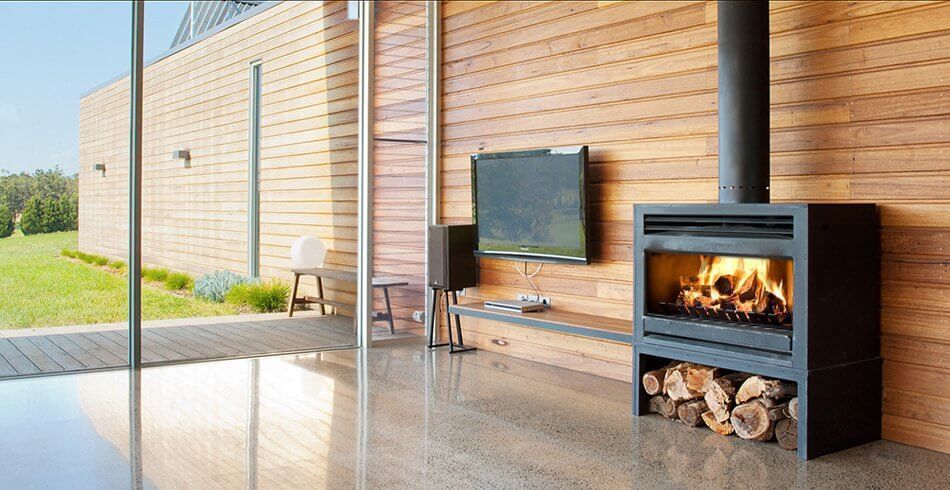 Patio With Wood Stove Fireplace, Stacked Logs, and Glass Wall — Complete Heating In Huntingfield, TAS