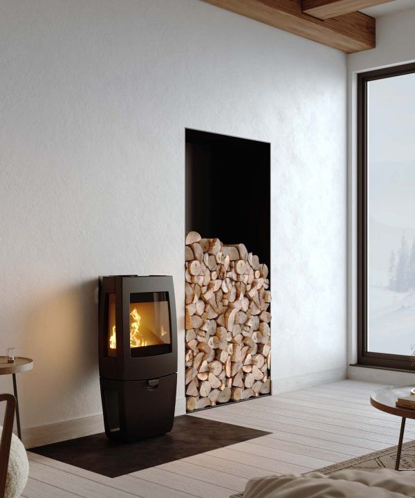 Living Room With a Black Wood Stove and Stacked Firewood Beside a Large Window — Complete Heating In Huntingfield, TAS
