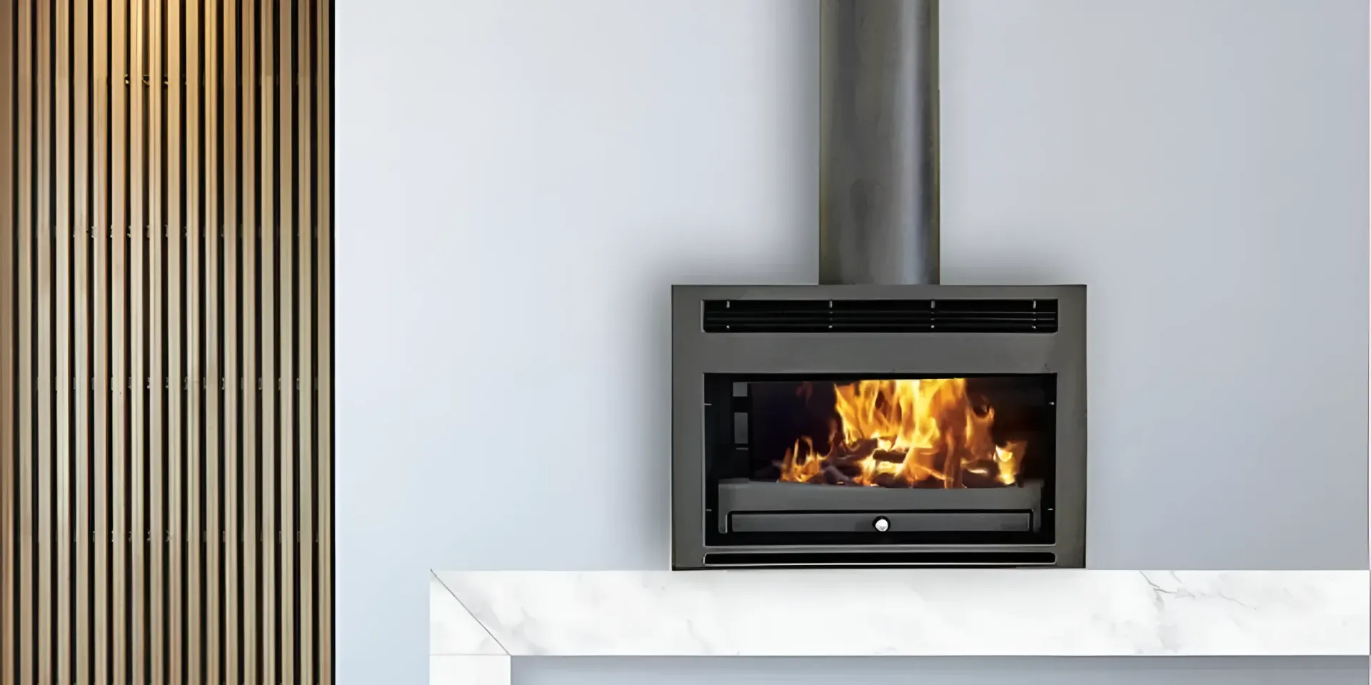 Fireplace With Black Insert, Stainless Flue, and Flame Above a White Hearth — Complete Heating In Huntingfield, TAS