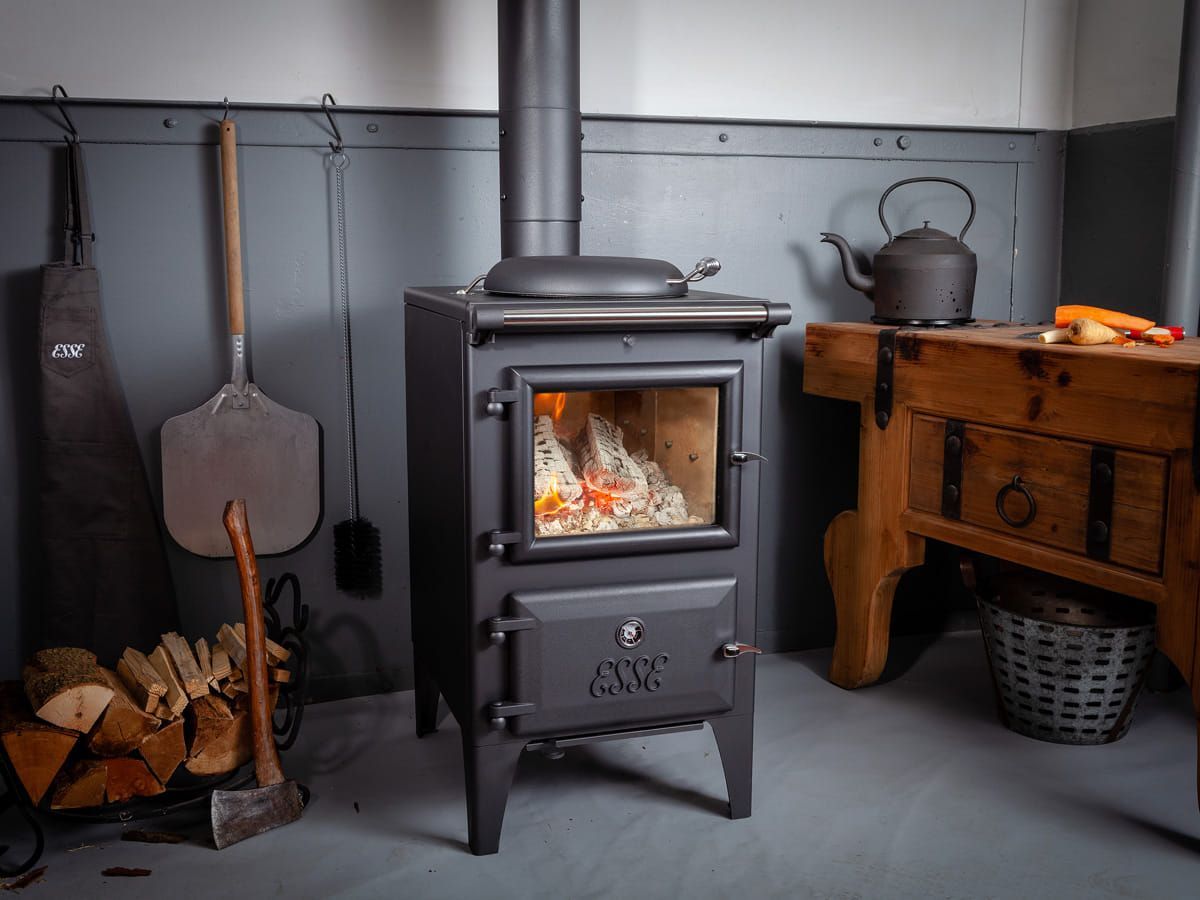 Cozy Wood Stove in Rustic Room With Logs, Tools, and a Wooden Table — Complete Heating In Huntingfield, TAS