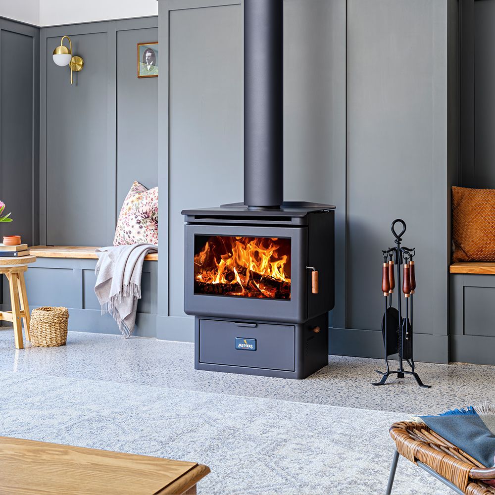 Living Room With a Black Wood Stove, Paneled Walls, and a Lit Fire Inside — Complete Heating In Huntingfield, TAS