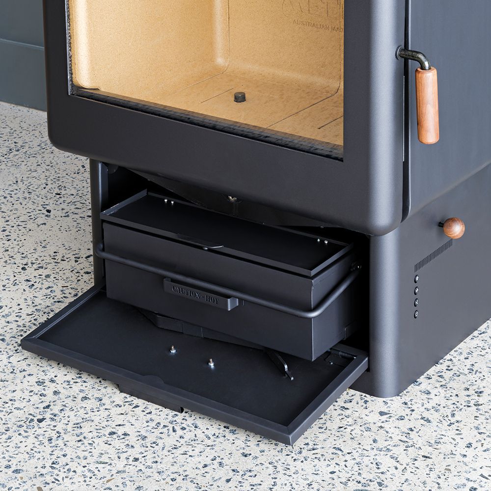 Black Wood Stove With Open Ash Drawer on Speckled Floor — Complete Heating In Huntingfield, TAS
