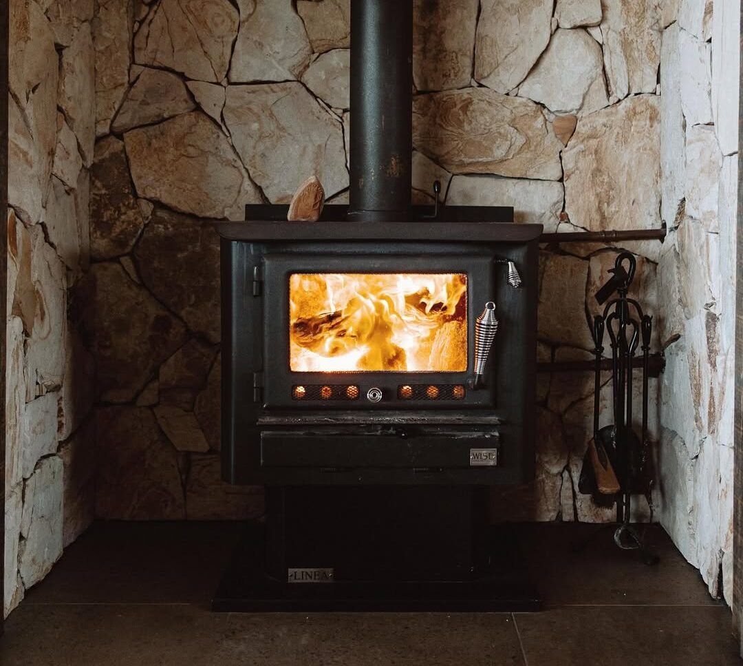 Lit Wood-burning Stove With Bright Flames in a Stone-walled Hearth — Complete Heating In Huntingfield, TAS