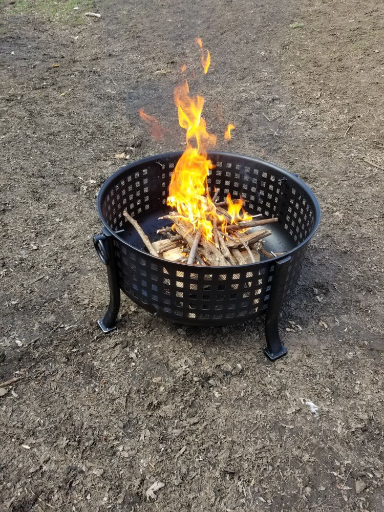 A Small, Black Metal Fire Pit Sitting on Dirt — Complete Heating In Huntingfield, TAS