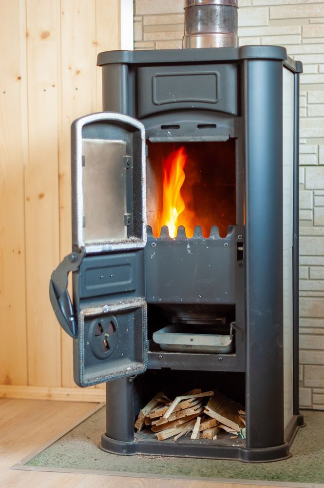 A Black, Wood-burning Stove With Its Door Open — Complete Heating In Huntingfield, TAS