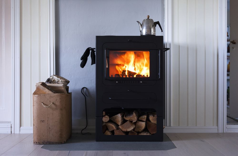 A Black Wood-burning Stove With a Lit Fire — Complete Heating In Huntingfield, TAS