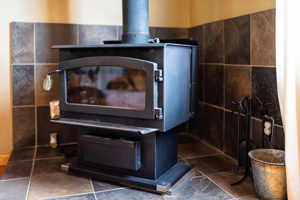 A Black Wood-burning Stove Sits on a Tiled Floor — Complete Heating In Huntingfield, TAS