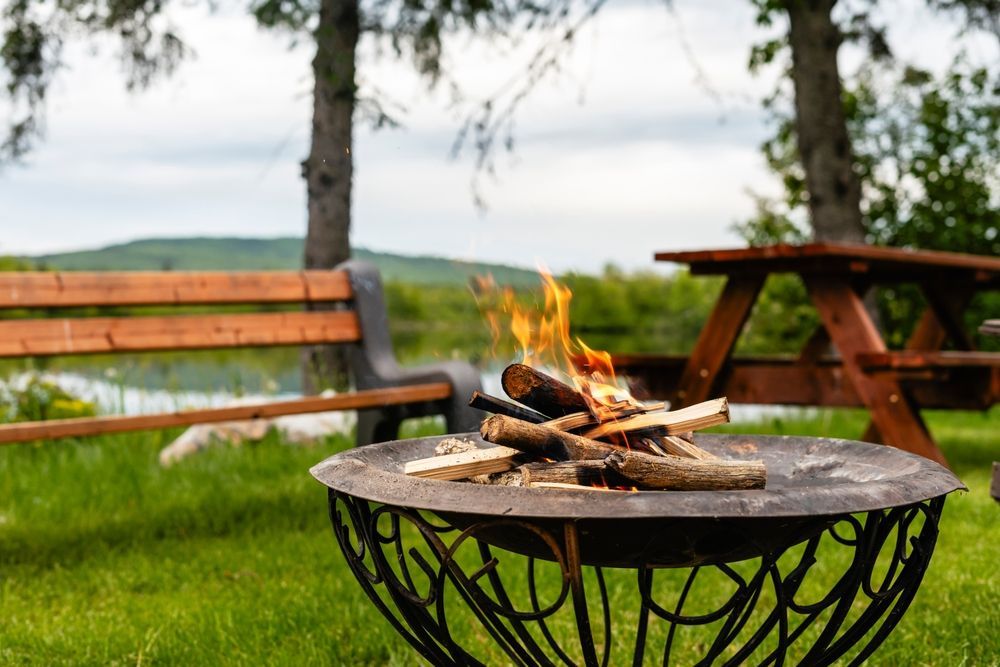 A Small Fire Burns in a Metal Fire Pit on a Grassy Lawn — Complete Heating In Huntingfield, TAS
