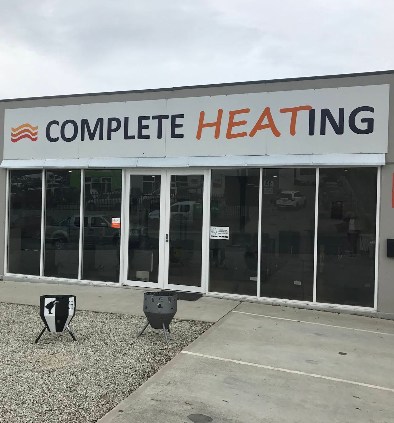 Storefront With a White Sign and Four Fire Pits on a Gravel Foreground — Complete Heating In Huntingfield, TAS