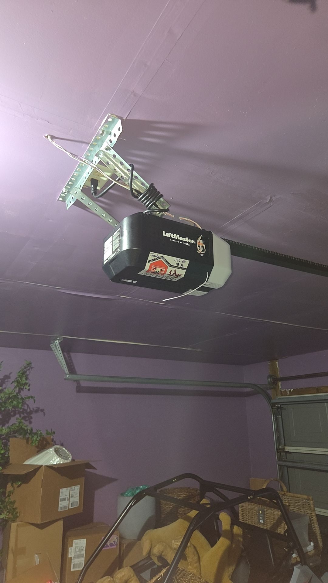 Garage ceiling with a black garage door opener and a mounted antenna on a purple wall.