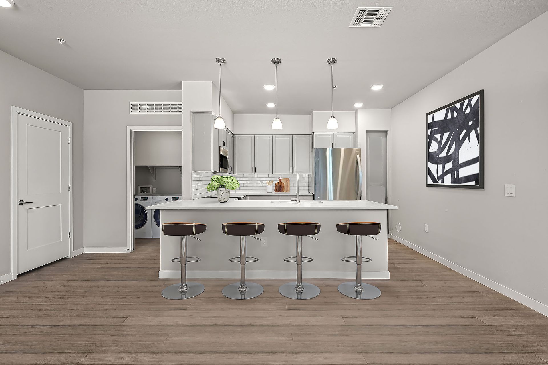 A kitchen with a large island , stools and a washer and dryer.