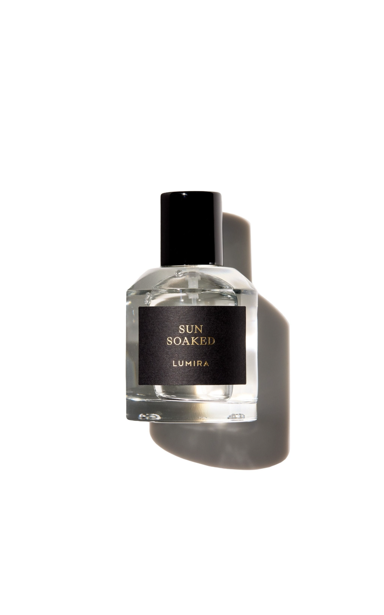 Clear glass perfume bottle with black cap, isolated on white background, casting a shadow